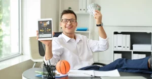 man sitting at desk with money and sports betting online