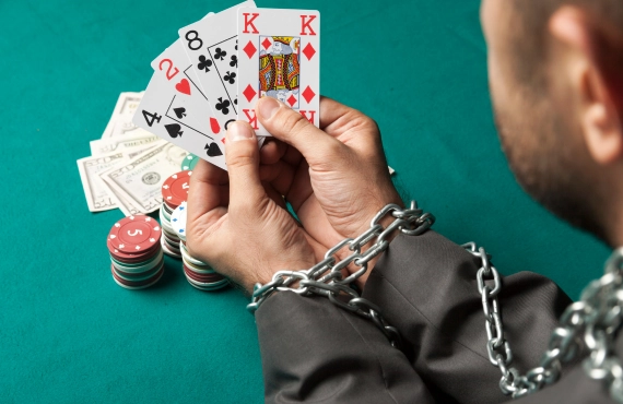 Gambler Hands Chained and Holding Cards on a Casino Table Gambler Hands Chained and Holding Cards on a Casino Table